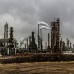 factories with smoke under cloudy sky